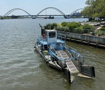 One of DC Water's skimmer boats on the Anacostia River with the Frederick Douglass Bridge in the background.