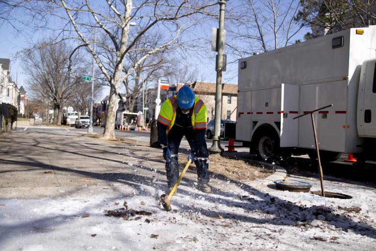 DC Water worker breaking up frozen ice on sidewalk