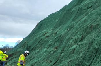 Photo of a worker on the slope an the slope with hydroseeding completed